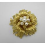 An 18 ct gold and pearl brooch, modelled as a flower with textured detail to the petals, set with