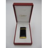 A black lacquer and gold plated Cartier lighter, in presentation box, the black lacquer body with