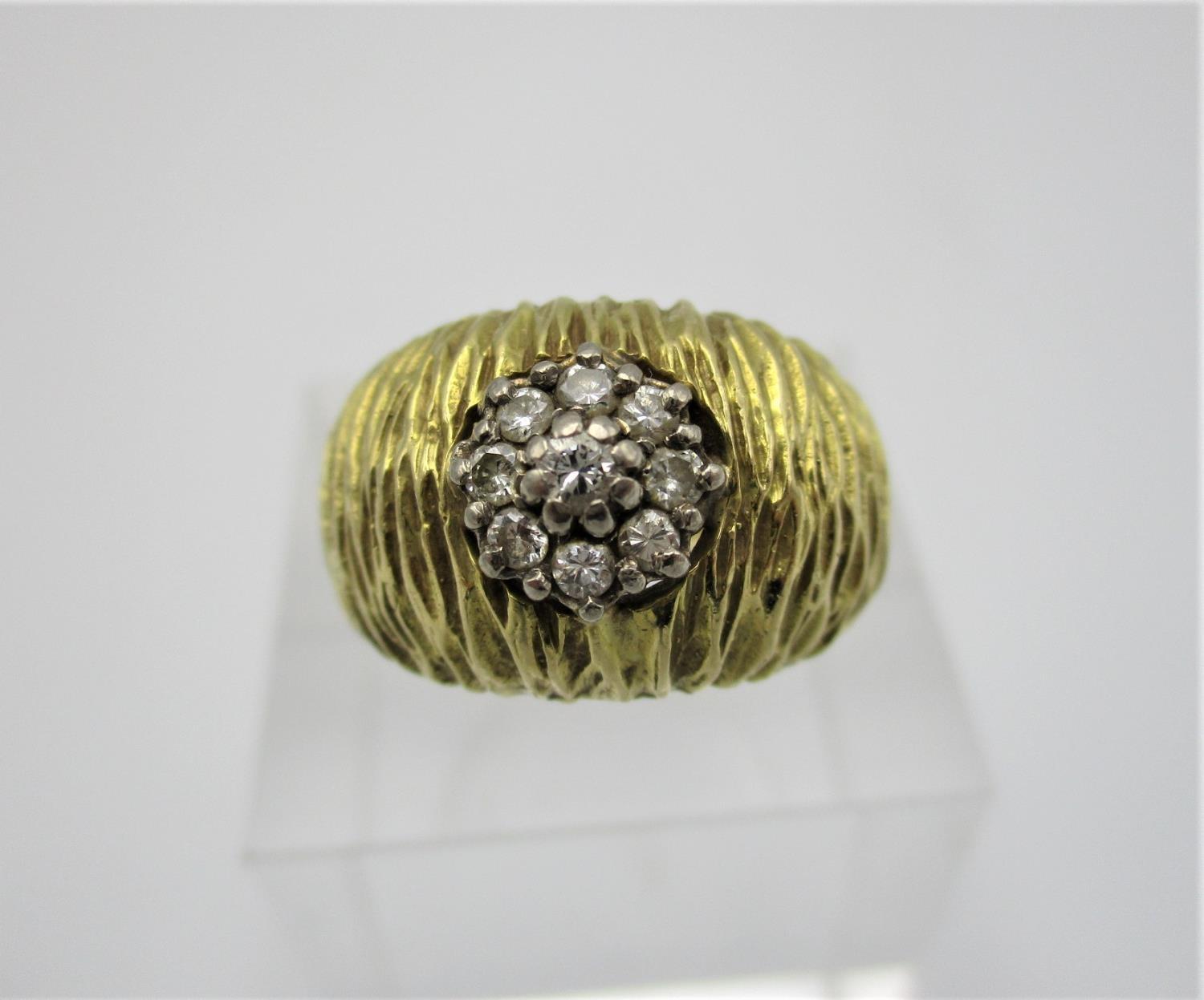 An 18t gold and diamond Modernist style ring, with textured finish, centred with nine cluster