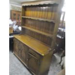 A reproduction oak dresser having a plate rack above three drawers and cupboards below 199.5cm h x