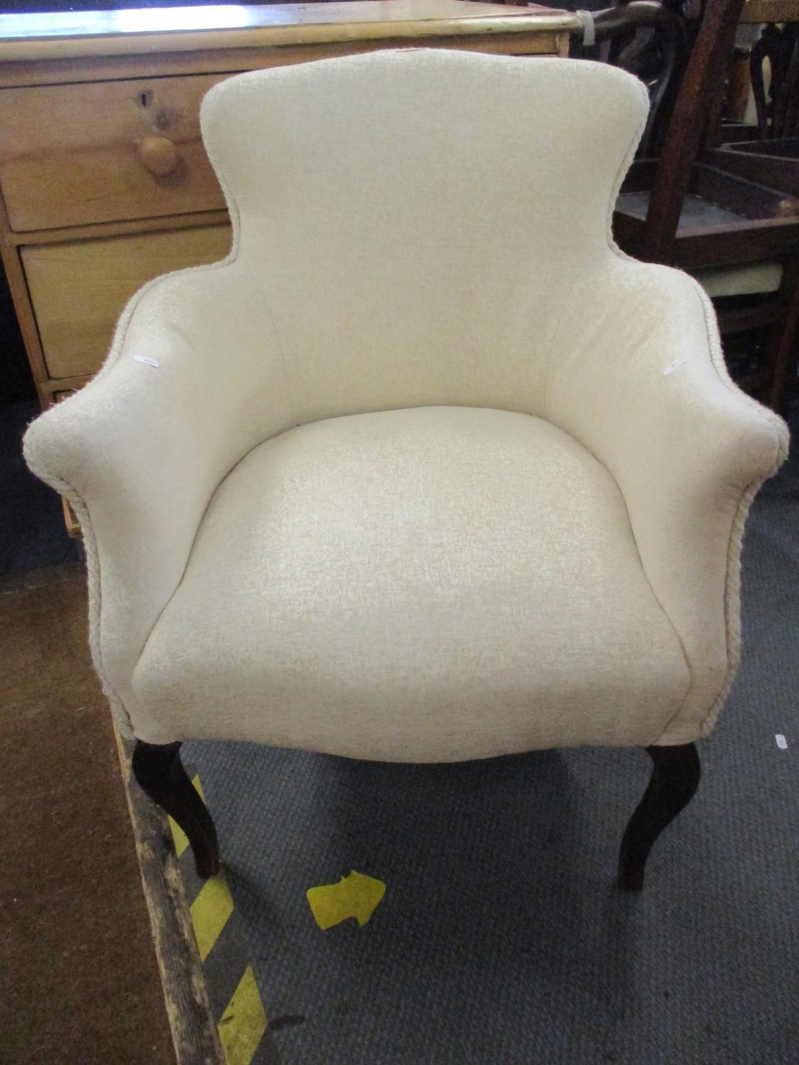 A cream upholstered arm chair with front cabriole legs