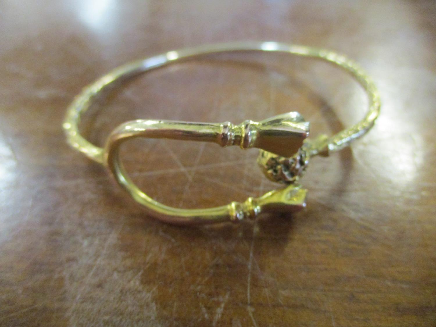 A yellow metal bracelet, the forked and terminating in two clenched fists, the other and terminating