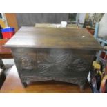 A 20th century oak boarded chest with a hinged top, over a carved front, on cut out ends 59 h x 74 w