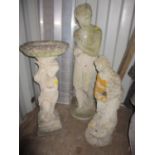 Two weathered concrete garden statues of classically dressed women, and a bird bath of a putti