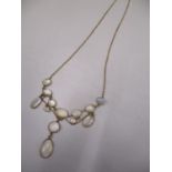 A yellow metal necklace set with thirteen moon stone coloured stones