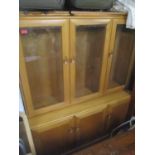 An Ercol display side cabinet, three glazed display doors with adjustable wooden shelves, above a
