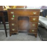 A reproduction mahogany inlaid kneehole desk with a door and seven drawers, on bracket feet, 76h x