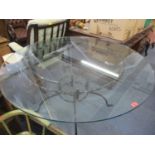 A large circular glass table on a wrought iron base