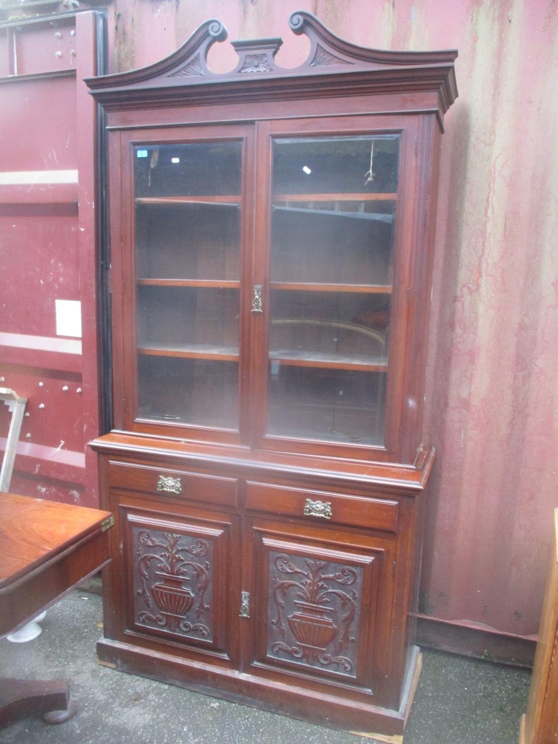 A late Victorian walnut bookcase cabinet with glazed doors, over two drawers and a pair of carved
