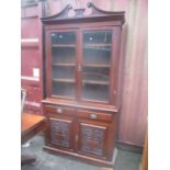 A late Victorian walnut bookcase cabinet with glazed doors, over two drawers and a pair of carved