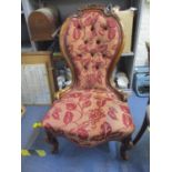 A Victorian walnut nursing chair with carved crest rail, upholstered seta and back, on short