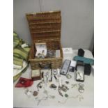 A wicker basket containing a selection of costume jewellery and wristwatches, to include a silver