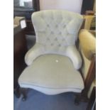 A reproduction button back low armchair on two front cabriole legs