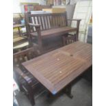 A teak garden table, 70 h x 180cm w, together with two benches and a pair of matching armchairs