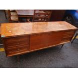 A mid 20th century teak sideboard with a fall flap flanked by six drawers, on turned tapered legs,