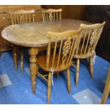 An Oval Extending Pine Dining Table On Turned Supports with Four Wheel Back Chairs