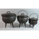 A Collection of Three Graduated Cast Iron Cauldrons on Three Feet, with Hooped Carrying Handles, The