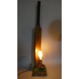 A Novelty Table Lamp in the Form of Cricket Bat and Ball on Astro Turf Plinth, 92cm High