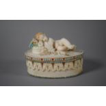 A Victorian Parian Ware Lidded Box with Sleeping Cherub and Hand Applied Coloured Enamels (AF)