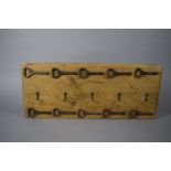 A Wall Hanging Five Cup or Coat Rack Mounted with Ten Vintage Bottle Openers, 52cms Wide