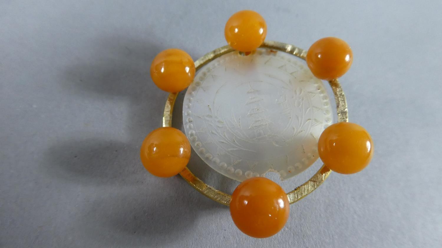 An Oriental Amber and Mother of Pearl Circular Brooch, with Engraved Pagoda Decoration, 3cms Diam