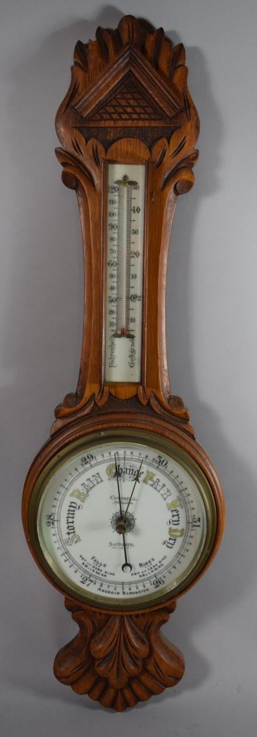 An Edwardian Carved Oak Aneroid Wheel Barometer with Thermometer, 84cms High