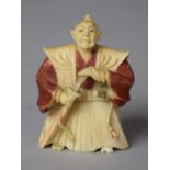 An Early 20th Century Japanese Carved Netsuke in the Form of a Robed Master with Sword in Hand,