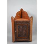 An Intricately Carved but Small Wall Hanging Corner Cabinet with Panelled Door and Galleried Back,