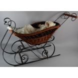 A Modern Wrought Iron and Basket Doll's Sleigh Containing Porcelain Head Doll, 89cm Long