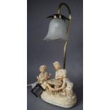 A Modern Resin Figural Table Lamp Depicting Children Cheating at Cards, 48cm high