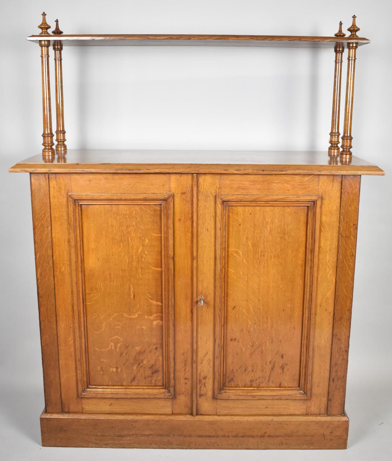 An Edwardian Oak Side Cupboard with Raised Shelf on Four Turned Supports, Panelled Doors to