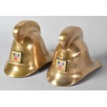 A Pair of Miniature Bronze Fireman's Helmets with Enamelled Badges, 7cm high