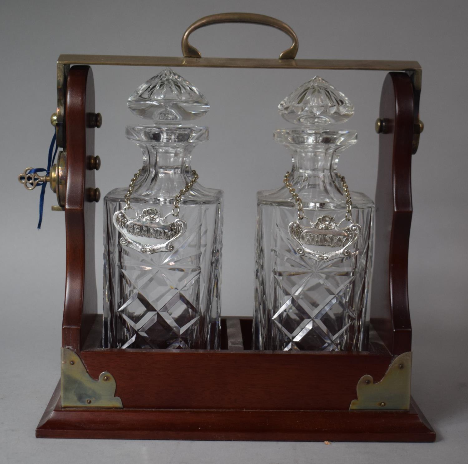 A Reproduction Silver Plate Mounted Two Bottle Tantalus with Whisky and Brandy Decanter Labels