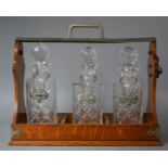 A Modern Three Bottle Oak and Silver Plated Tantalus with Decanter Labels for Whisky, Brandy and