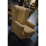 An Upholstered Wing Armchair with Brass Casters