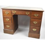 An Oak Kneehole Writing Desk with Tooled Leather Top and Pierced Brass Drop Handles, 107cm wide