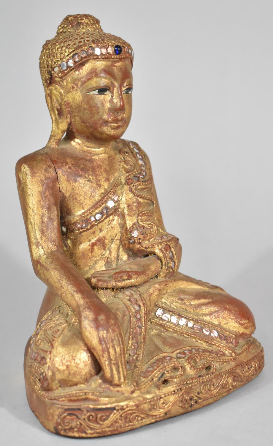 A Carved Wooden Gilt Decorated Study of Seated Buddha with Inlaid Mirror Fragments, 22cm high