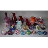 A Collection of Various Coloured Glassware and Paperweights to include Cranberry Glass Jugs, Slag
