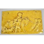 A Yellow Glazed Ceramic Plaque Depicting Cherubs and Goat, 28cm long