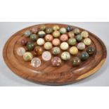 A Modern Circular Wooden Solitaire Board Complete with Collection of Stone and Crystal Marbles, many
