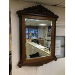 A LARGE BEVELLED MIRROR WITH CARVINGS OF ELEPHANTS TO THE TOP 92 X 69 CMS