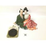 AN EROTIC CERAMIC FIGURE OF A SEATED JAPANESE COUPLE WITH A REVEALING UNDERSIDE, 17.5CM HIGH,