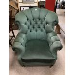 A GREEN UPHOLSTERED BUTTON BACK ARMCHAIR