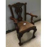A CARVED MAHOGANY CHILDS ARMCHAIR WITH UPHOLSTERED BROWN SEAT, THE FRONT TWO FEET WITH CLAW AND BALL