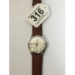 A GENTS UNIVERSAL GENEVE MANUAL WIND WRISTWATCH ON LATER LEATHER STRAP, THE WHITE DIAL WITH BATON