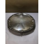 AN EARLY GEORGE III SILVER SALVER WITH DECORATIVE SHELL MOTIF BORDER AND RAISED UPON THREE FEET,