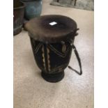 A LARGE VINTAGE HAND CARVED SKIN TOPPED DRUM WITH STRAP 44CMS HIGH