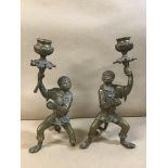 A PAIR OF NOVELTY BRASS CANDLESTICKS IN THE FORM OF MONKEYS IN HUMAN DRESS, 23CM HIGH