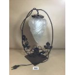 A METAL TABLE LAMP, THE HANGING GLASS SHADE ON A BLACK METAL FRAME WITH GRAPE AND VINE DECORATION,