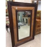 AN UNUSUALLY LARGE DARK WOOD FRAMED WALL MIRROR OF RECTANGULAR FORM, THE BORDER WITH LEATHER AND